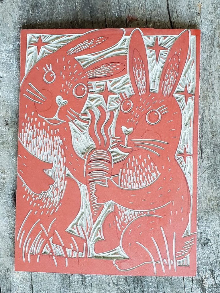 linocut block with design with 2 rabbits and a carrot