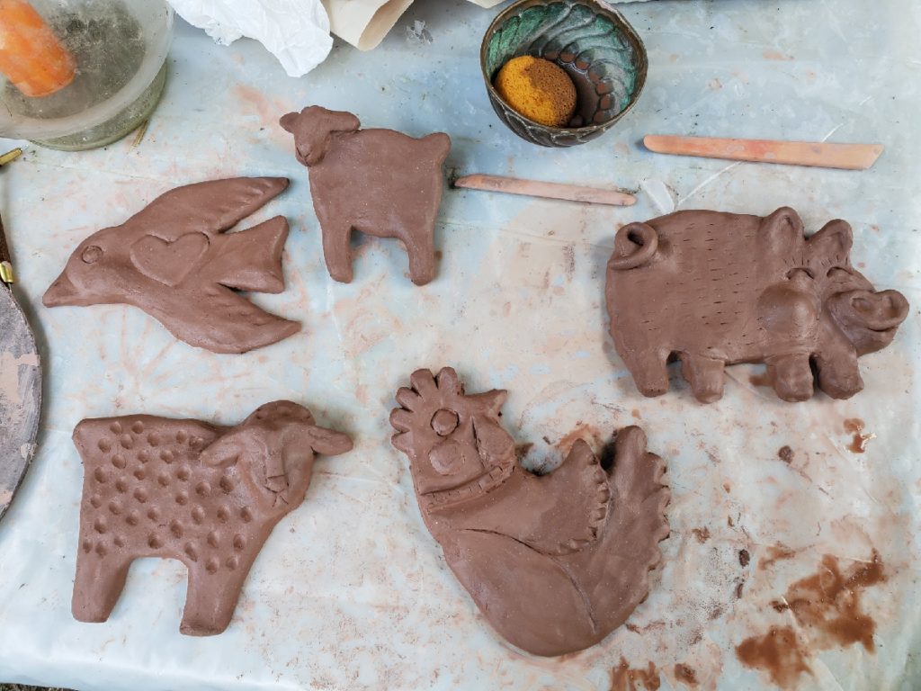 clay work in progress sculptures of a dove, lamb pig and chicken