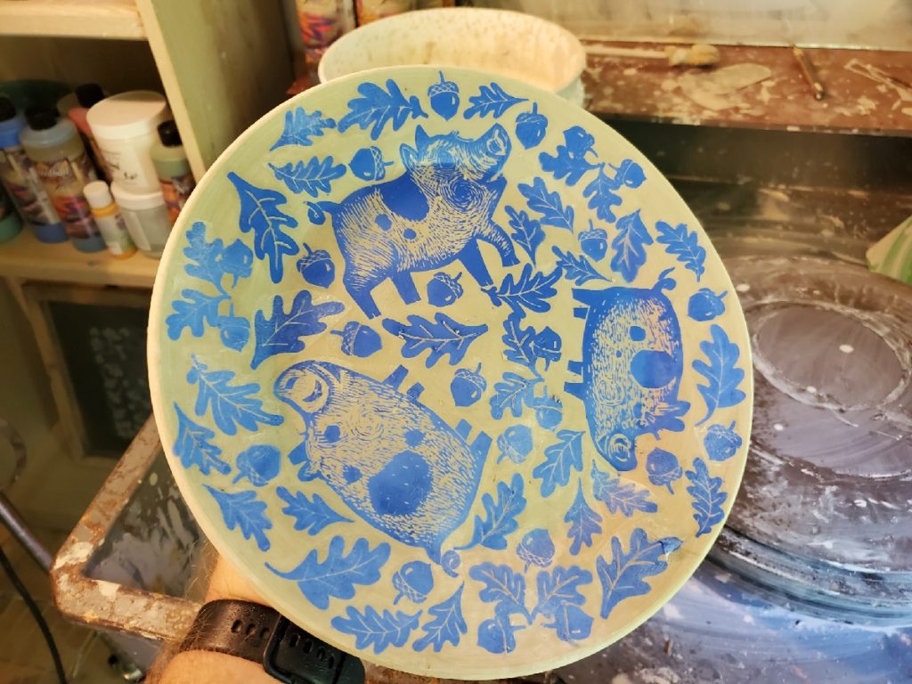 an underglaze plate covered with blue pig and acorn decals