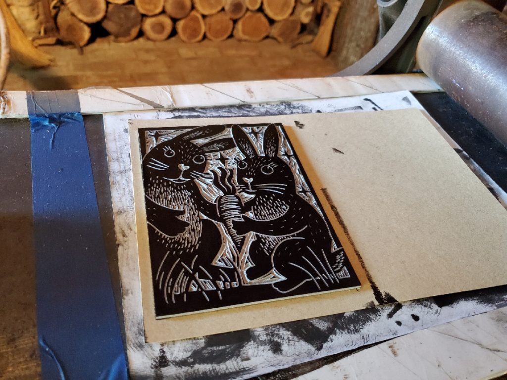 linocut of two bunnies sharing a carrot inked and ready to print