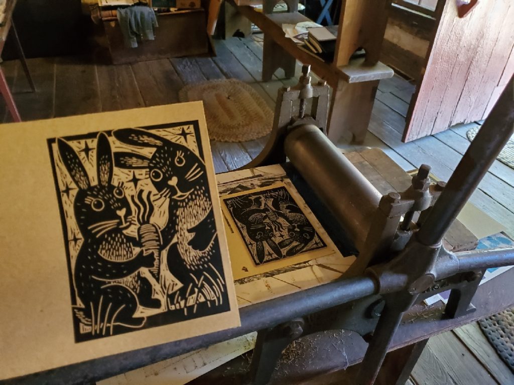 test proof of linocut of two bunnies with a carrot