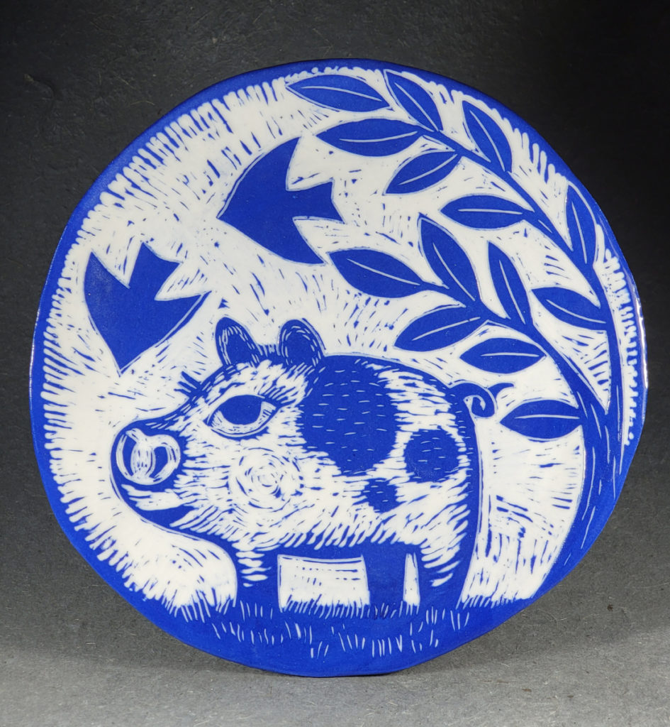 porcelain blue plate with design of a pig under a tree