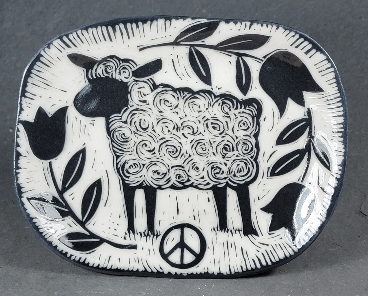 porcelain folk art style plate with sgraffito sheep and peace symbol