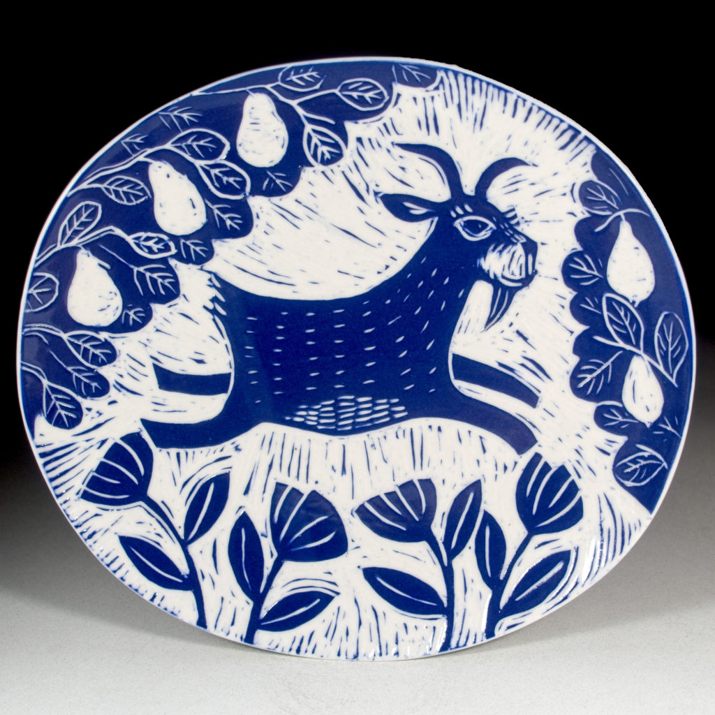 porcelain plate with blue goat jumping under a pear tree by kentucky artist ken swinson