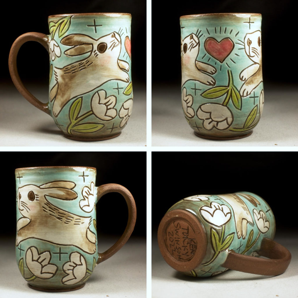 handmade stoneware cup with decorative rabbits flowers and a heart. made by kentucky artist ken swinson