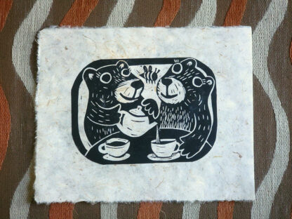 hand printed linocut on handmade paper-depicts two bears having tea. One is pouring tea into the other’s cup.