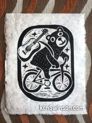 linocut depicting a black bear carrying a guitar while riding a bicycle.