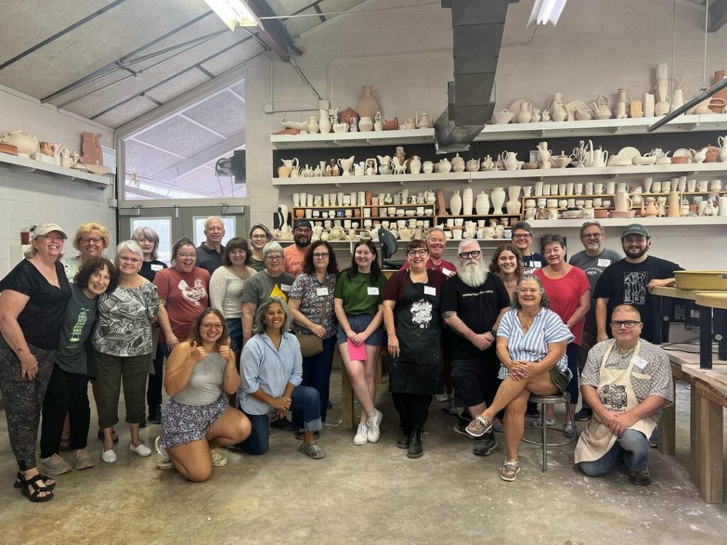 group photo of happy students posing in the Arrowmont clay studio with superstar teachers, Mark Errol and Kathy King.