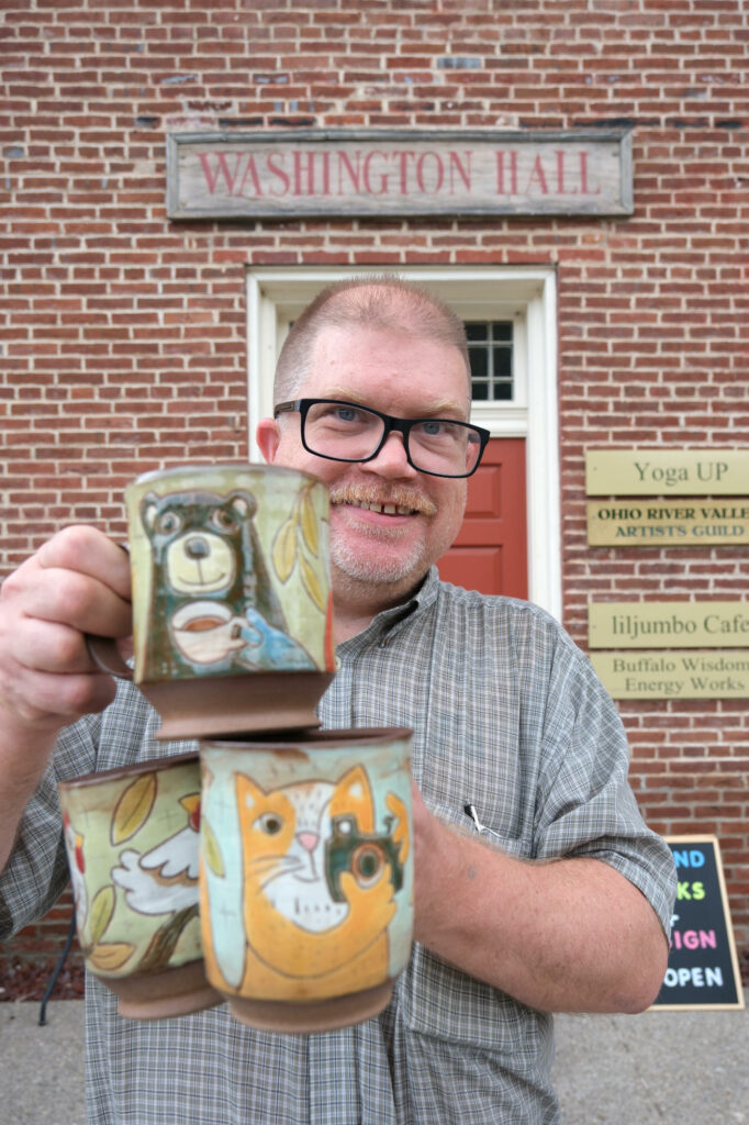 Artist, Ken Swinson, standing in front of washington hall in old washington ky with cups in his hands